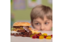 Child looking at fast food, chocolate, and gummy candies on a table
